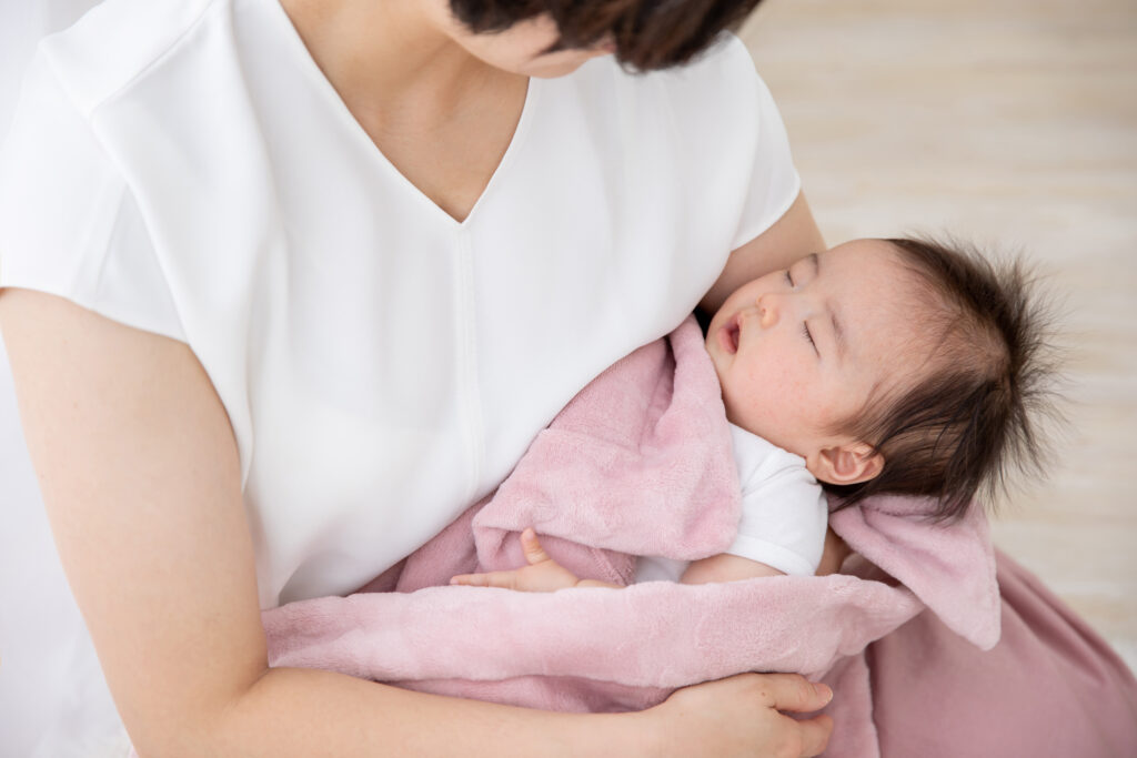 母親の腕の中で眠る赤ちゃん