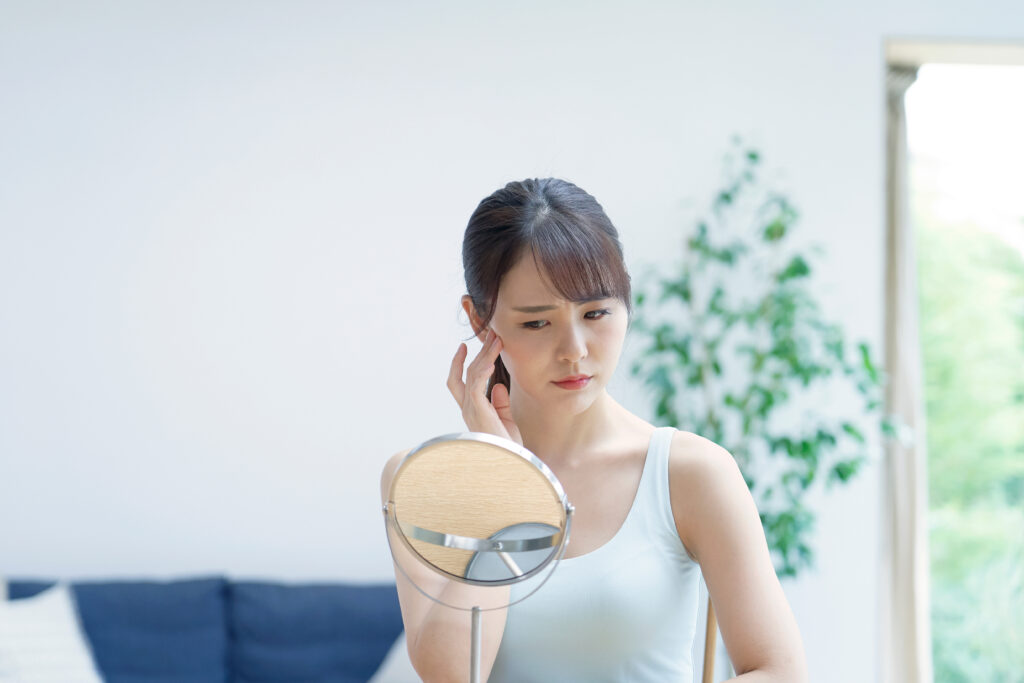 女性が悩んだ顔で鏡を見ている