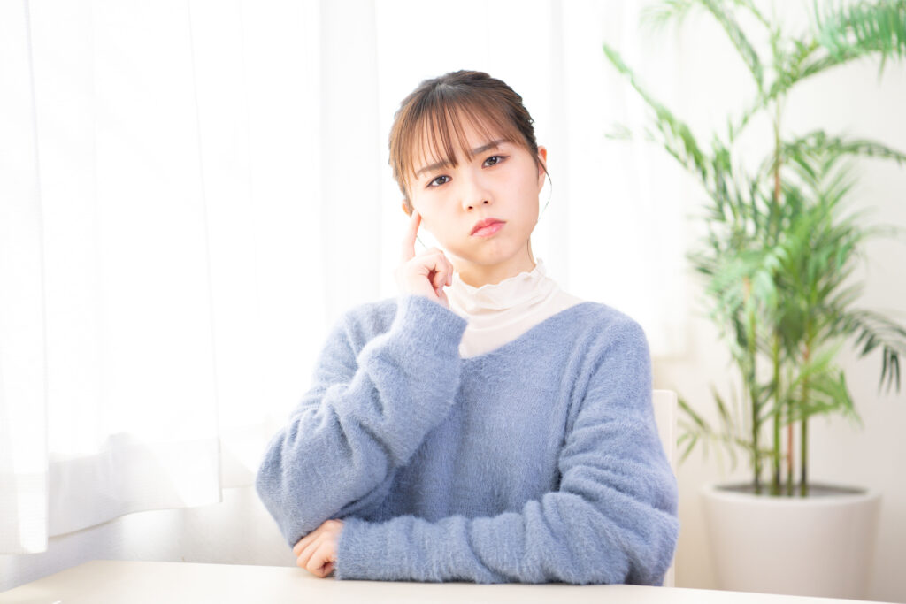 部屋で考え事をしている若い女性