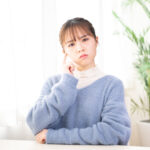 部屋で考え事をしている若い女性